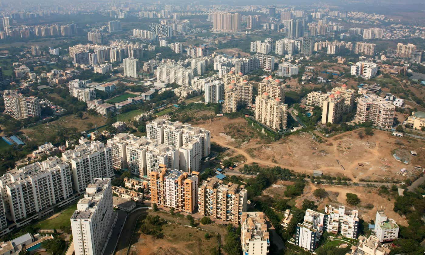 Aerial view of open, partly cleared land between clusters of high-rise apartment blocks at a city's edge