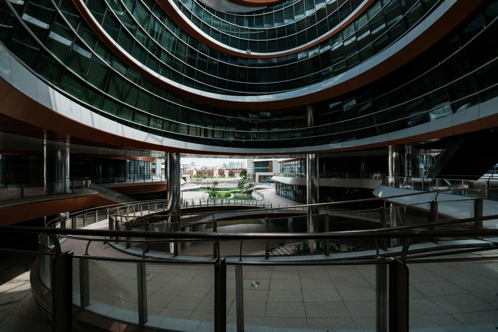 Curved glass office floors ringing an open atrium that looks out to a landscaped courtyard